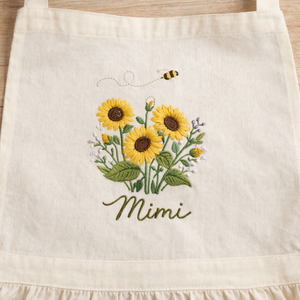 Personalized hand embroidered linen apron featuring sunflowers, wildflowers, honey bee embroidery, and custom name personalization.