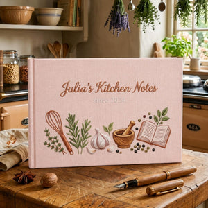 Personalized hand embroidered kitchen notes recipe journal featuring rosemary, herbs, garlic, whisk, mortar and pestle, peppercorns, and open recipe book on linen cover