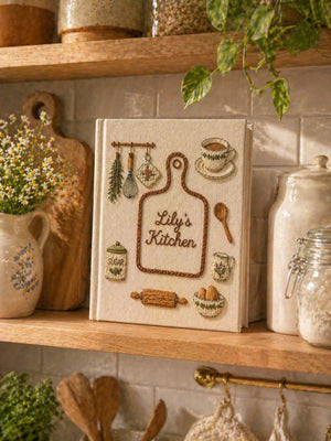 Hand embroidered recipe book featuring personalized cutting board design with rolling pin, whisk, sugar jar, teacup, eggs and cottage kitchen accents.