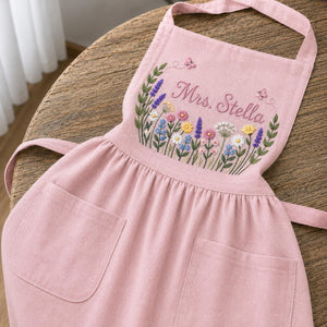 Personalized hand embroidered linen apron featuring colorful wildflowers, butterflies, lavender blooms, and custom name embroidery.