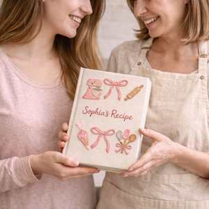 Personalized hand embroidered recipe book featuring a pink stand mixer, pastry piping bag, baking utensils and ribbon bow accents on a linen cover.