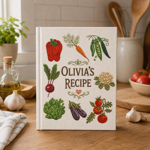 Personalized hand embroidered recipe book featuring carrots, tomatoes, radish, peas, cauliflower, onion, fresh herbs and garden harvest vegetables on natural linen cover.