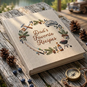 Personalized hand embroidered recipe book featuring fishing rod, barbecue grill, vintage truck, woodworking tools, pine branches and outdoor dad themed design on linen cover.