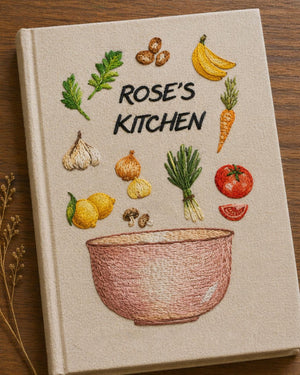 Personalized hand embroidered recipe book featuring fresh vegetables herbs garlic mushrooms lemons tomatoes and a rustic mixing bowl design on a linen cover.