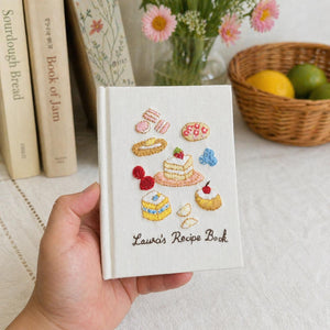 Hand embroidered baking journal featuring strawberry cake macarons pastries berries and dessert motifs on linen cover