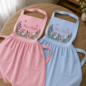Personalized hand embroidered linen apron featuring colorful wildflowers, butterflies, lavender blooms, and custom name embroidery.