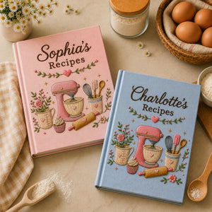 Personalized hand embroidered recipe book featuring a pink stand mixer, whisk, spatula, rolling pin, cupcake, measuring cup and floral baking motifs on a linen cover.