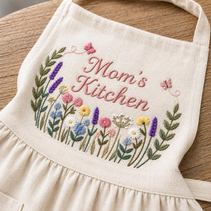 Personalized hand embroidered linen apron featuring colorful wildflowers, butterflies, lavender blooms, and custom name embroidery.