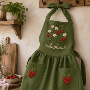 Personalized hand embroidered strawberry garden linen apron featuring strawberries, white flowers, botanical vines and custom text, cottagecore kitchen apron gift.