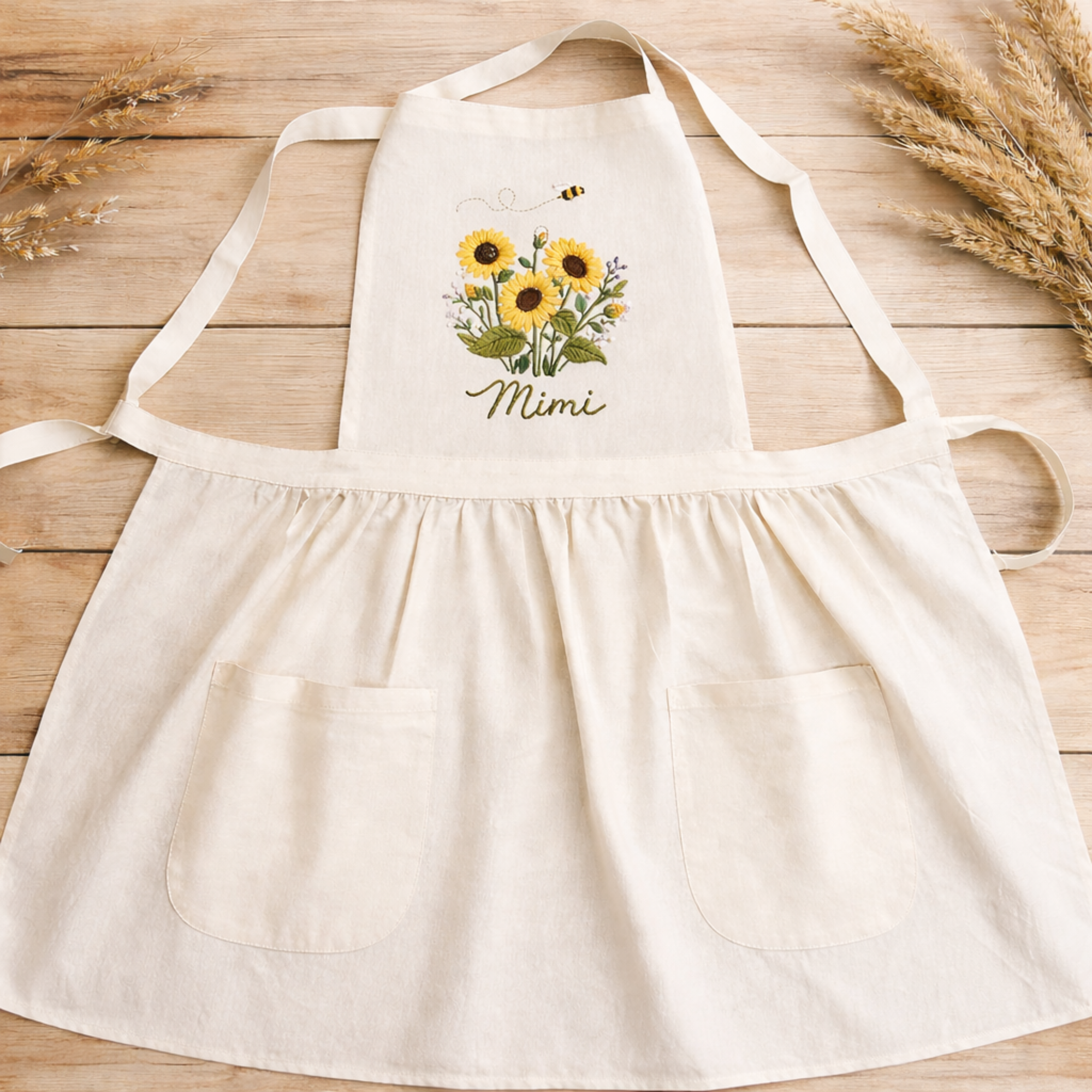 Personalized hand embroidered linen apron featuring sunflowers, wildflowers, honey bee embroidery, and custom name personalization.