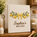 Personalized lemon blossom hand embroidered recipe book featuring lemons, lemon slices, white flowers, greenery, and decorative bow embroidery on linen cover