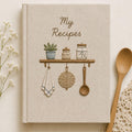 Hand embroidered recipe book featuring rustic pantry shelf with storage jars, botanical greenery, woven kitchen accents and cottage farmhouse decor.