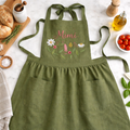 Personalized hand embroidered wildflower linen apron featuring custom name embroidery and delicate meadow flower design on a sage green apron.