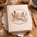 Personalized hand embroidered recipe book featuring chef hat, rolling pins, whisk, wooden spoon, floral accents, and custom name embroidery on a linen hardcover notebook.