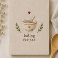 Hand embroidered recipe book featuring mixing bowl whisk heart and botanical accents on linen hardcover cover