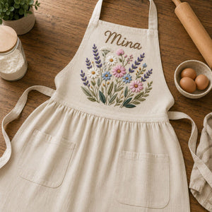 Personalized hand embroidered linen apron featuring wildflower bouquet embroidery, lavender flowers, daisies, and custom name embroidery.