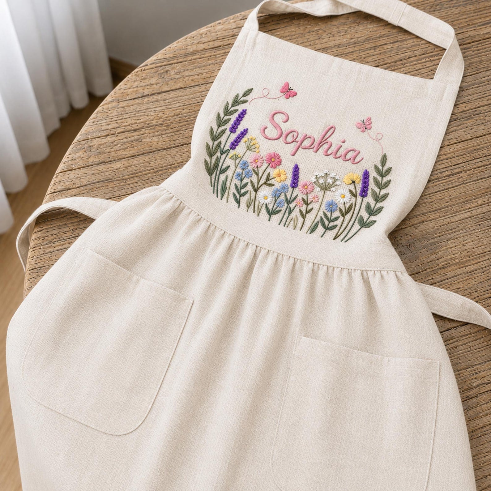 Personalized hand embroidered linen apron featuring colorful wildflowers, butterflies, lavender blooms, and custom name embroidery.