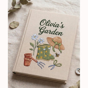 Personalized hand embroidered garden journal featuring rain boots flowers gardening tools and straw hat on linen cover
