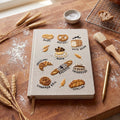 Hand embroidered recipe book featuring artisan breads including bagels, pretzels, croissants, baguettes, sourdough, muffins and cinnamon rolls.