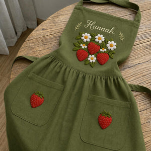 Personalized hand embroidered linen apron featuring strawberries, daisy flowers, botanical garden embroidery, and custom name personalization.