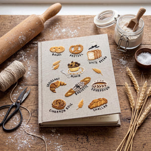 Hand embroidered recipe book featuring artisan breads including bagels, pretzels, croissants, baguettes, sourdough, muffins and cinnamon rolls.
