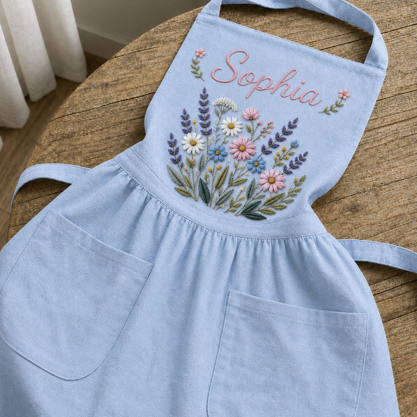 Personalized hand embroidered linen apron featuring wildflower bouquet embroidery, lavender flowers, daisies, and custom name embroidery.
