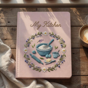 Personalized hand embroidered recipe book featuring floral baking wreath with mixing bowl whisk rolling pin and baking ingredients on linen cover