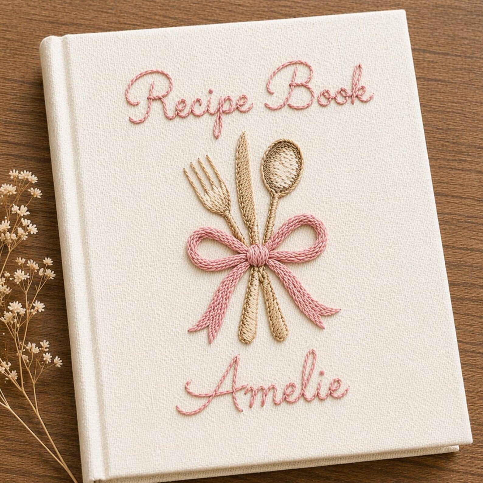 Personalized hand embroidered recipe book featuring fork, knife and spoon tied with a ribbon on a linen cover with custom name embroidery.