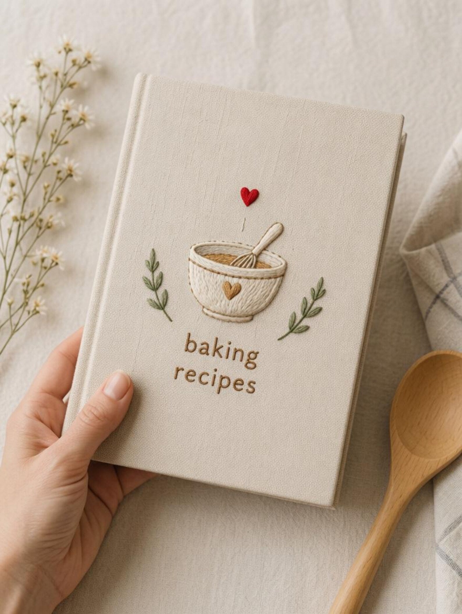 Hand embroidered recipe book featuring mixing bowl whisk heart and botanical accents on linen hardcover cover