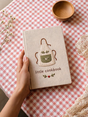 Hand embroidered recipe book featuring a minimalist cottagecore apron design on a linen hardcover notebook.