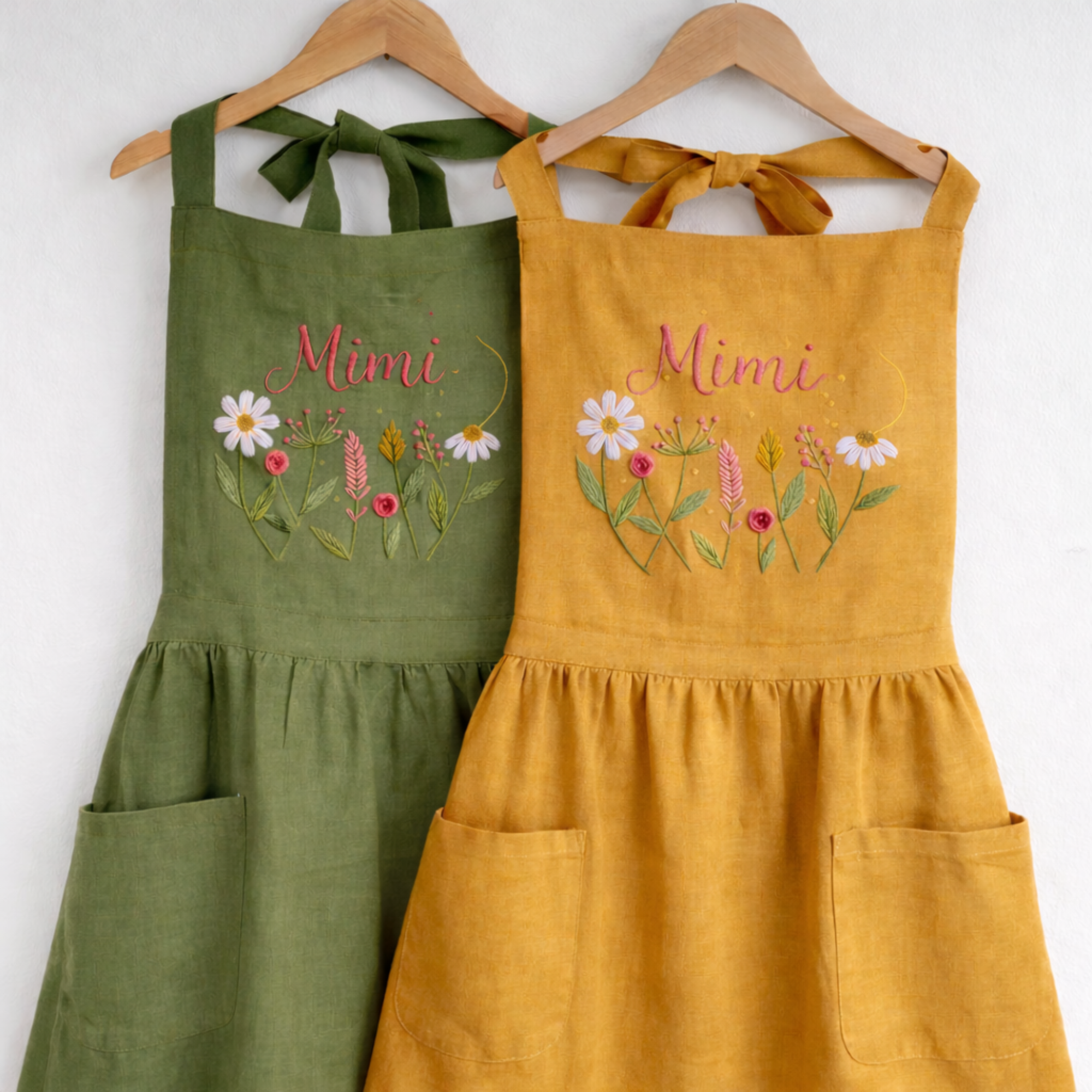 Personalized hand embroidered wildflower linen apron featuring custom name embroidery and delicate meadow flower design on a sage green apron.