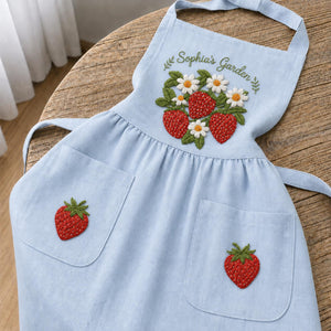 Personalized hand embroidered linen apron featuring strawberries, daisy flowers, botanical garden embroidery, and custom name personalization.