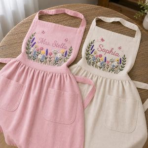 Personalized hand embroidered linen apron featuring colorful wildflowers, butterflies, lavender blooms, and custom name embroidery.