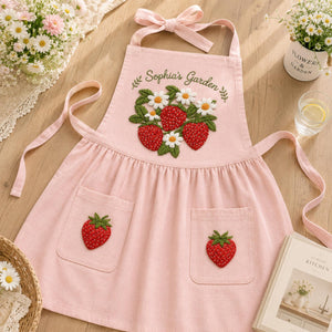 Personalized hand embroidered linen apron featuring strawberries, daisy flowers, botanical garden embroidery, and custom name personalization.