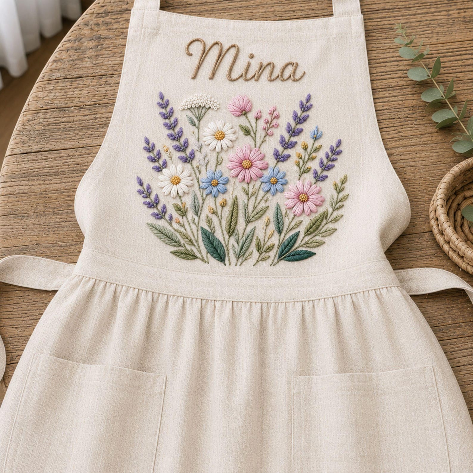 Personalized hand embroidered linen apron featuring wildflower bouquet embroidery, lavender flowers, daisies, and custom name embroidery.