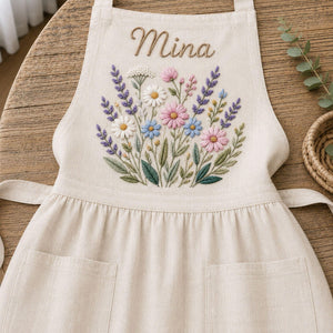 Personalized hand embroidered linen apron featuring wildflower bouquet embroidery, lavender flowers, daisies, and custom name embroidery.