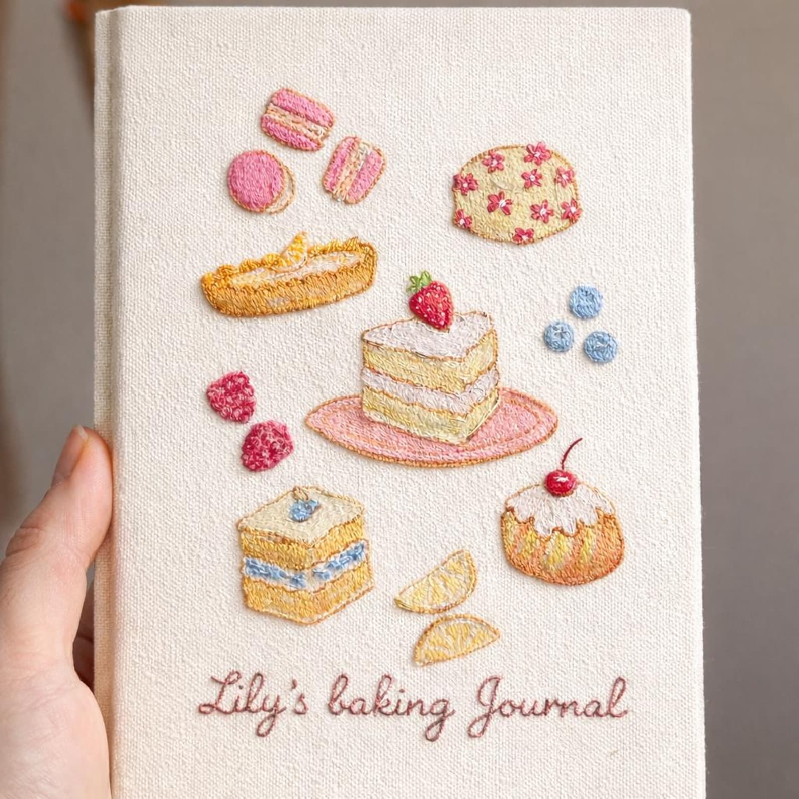Hand embroidered baking journal featuring strawberry cake macarons pastries berries and dessert motifs on linen cover